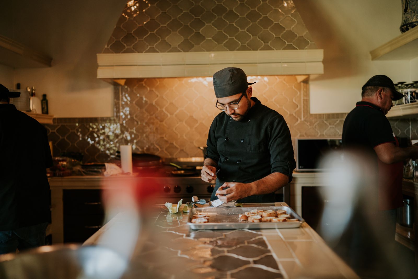 A cook building plates to spec on a warm-lit line, the consistency a recipe sheet template is built to protect